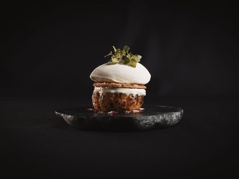 Our restaurant in Pitztal Gourmet dessert with meringue and herbs on black stone plate