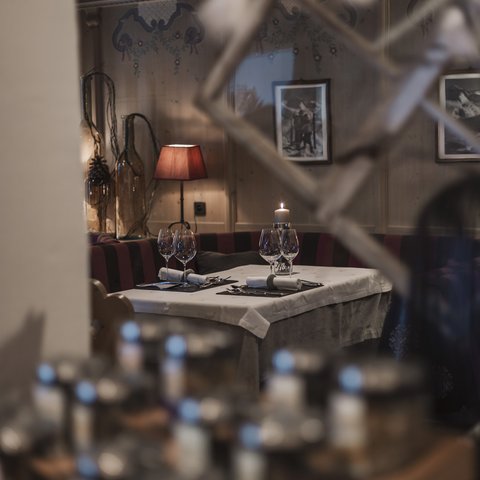 Bilder aus der Sportalm Gemütlicher Restauranttisch mit Kerze, Weingläsern und roter Lampe im Hintergrund