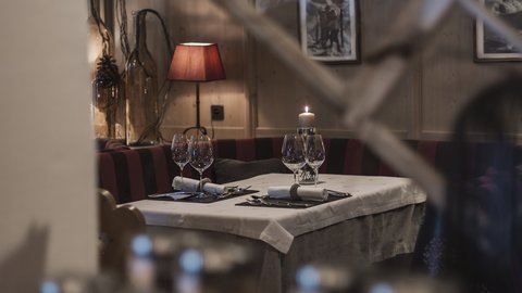 Bilder aus der Sportalm Gemütlicher Restauranttisch mit Kerze, Weingläsern und roter Lampe im Hintergrund