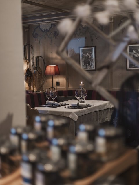 Bilder aus der Sportalm Gemütlicher Restauranttisch mit Kerze, Weingläsern und roter Lampe im Hintergrund