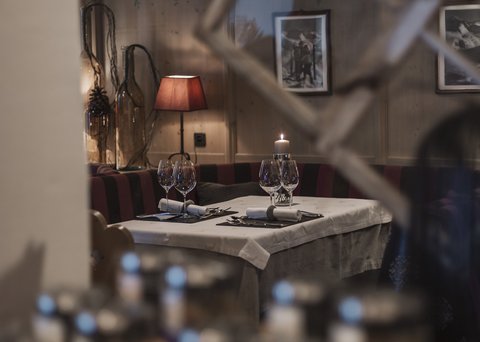 Bilder aus der Sportalm Gemütlicher Restauranttisch mit Kerze, Weingläsern und roter Lampe im Hintergrund