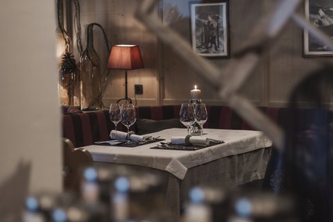 Bilder aus der Sportalm Gemütlicher Restauranttisch mit Kerze, Weingläsern und roter Lampe im Hintergrund