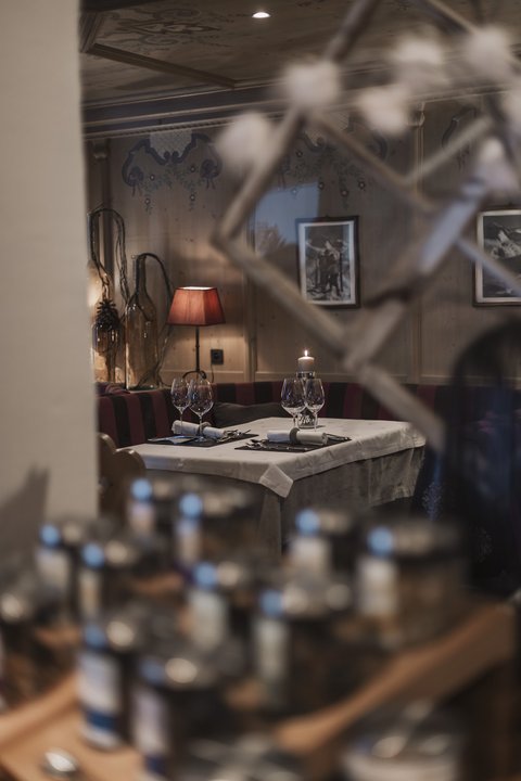 Bilder aus der Sportalm Gemütlicher Restauranttisch mit Kerze, Weingläsern und roter Lampe im Hintergrund