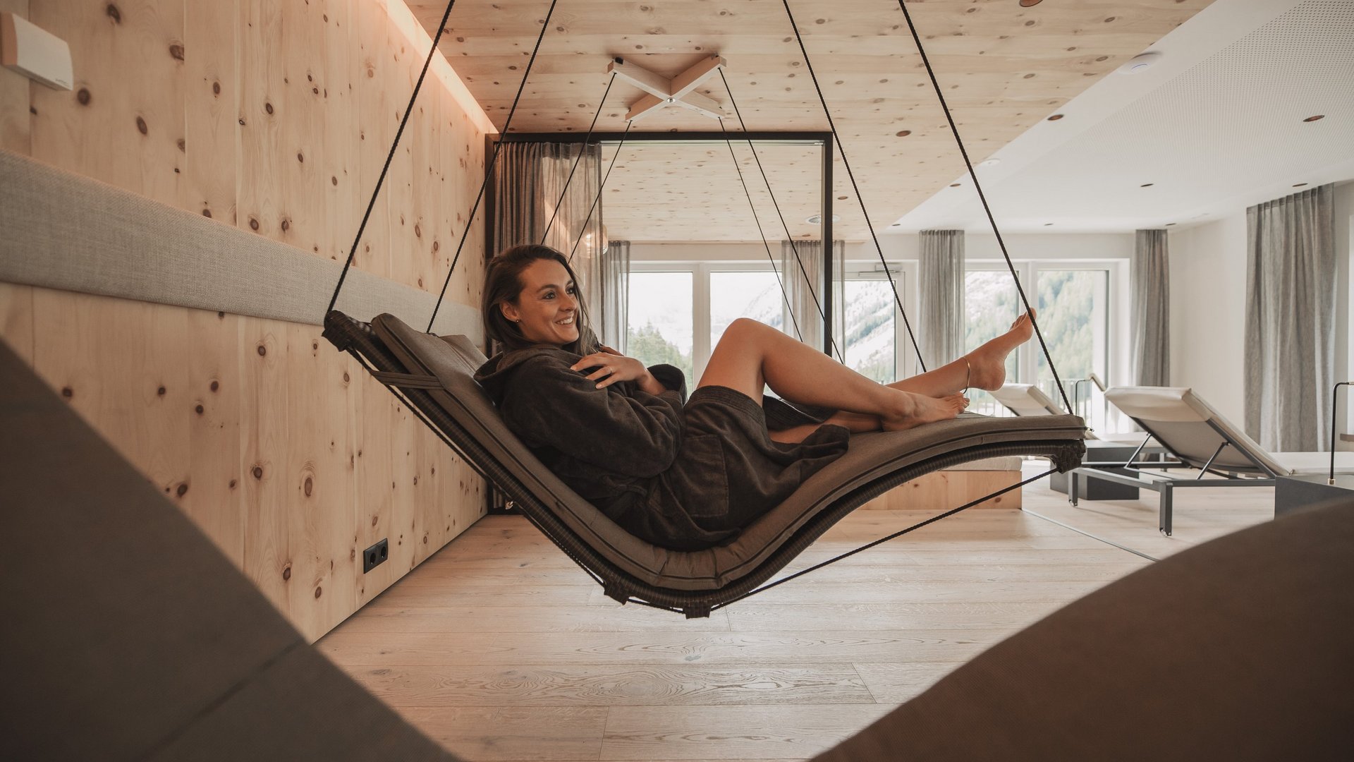 Freude schenken Frau entspannt auf hängender Liege in modernem Wellnessraum