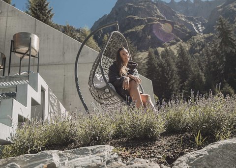 Pictures from Sportalm Woman relaxing in hanging chair by house with mountain view on a sunny day