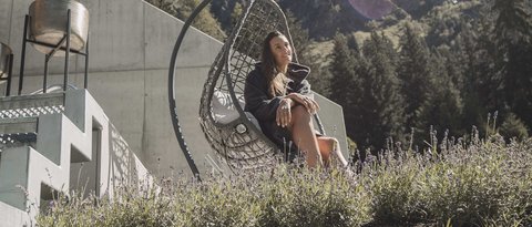 Pictures from Sportalm Woman relaxing in hanging chair by house with mountain view on a sunny day