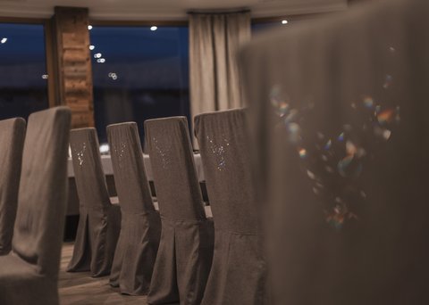 Bilder aus der Sportalm Reihe grauer Stühle mit Hussen in einem stilvollen Esszimmer bei Nacht