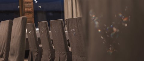 Bilder aus der Sportalm Reihe grauer Stühle mit Hussen in einem stilvollen Esszimmer bei Nacht