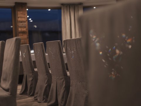 Bilder aus der Sportalm Reihe grauer Stühle mit Hussen in einem stilvollen Esszimmer bei Nacht