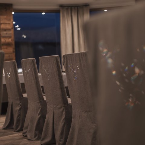 Bilder aus der Sportalm Reihe grauer Stühle mit Hussen in einem stilvollen Esszimmer bei Nacht