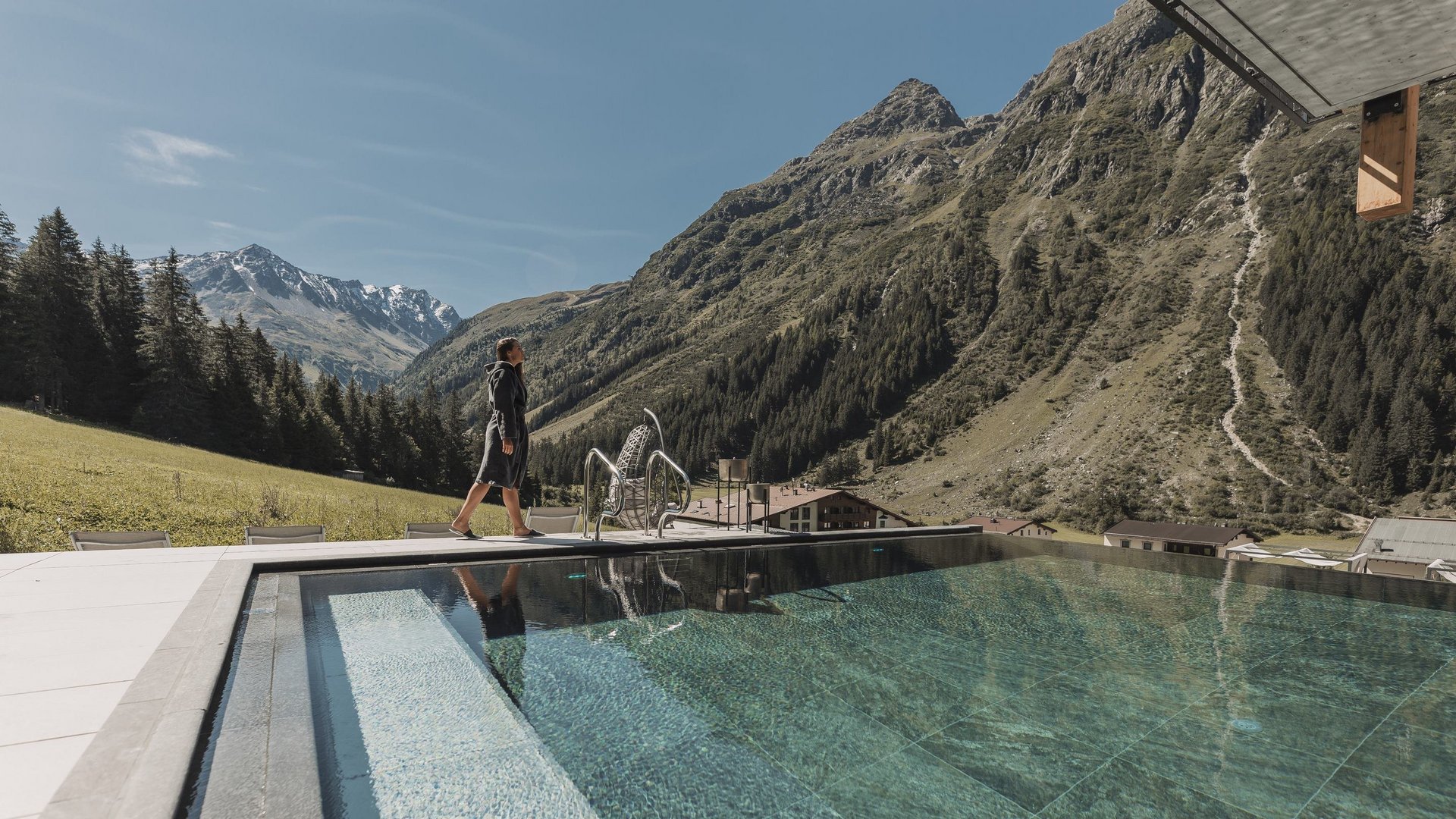 Wellness hotel in Pitztal: pure relaxation Person by pool with mountain view and clear sky