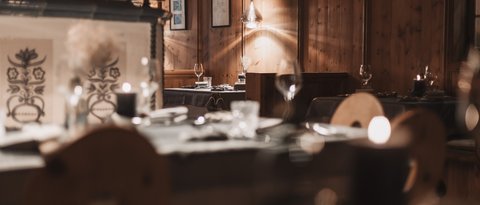 Bilder aus der Sportalm Gemütliches Restaurant mit Holzwänden und Tischgedecken bei Kerzenlicht