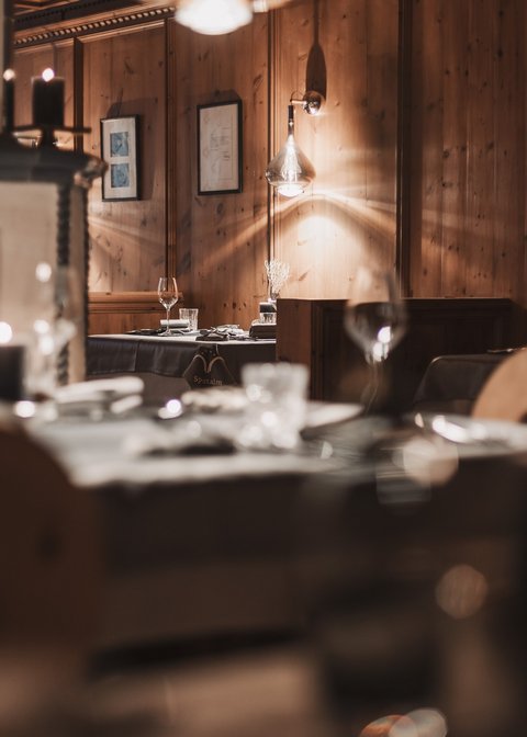 Bilder aus der Sportalm Gemütliches Restaurant mit Holzwänden und Tischgedecken bei Kerzenlicht