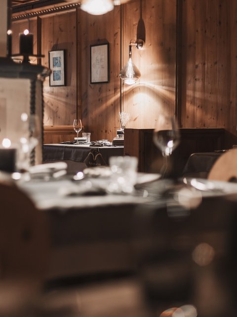 Bilder aus der Sportalm Gemütliches Restaurant mit Holzwänden und Tischgedecken bei Kerzenlicht