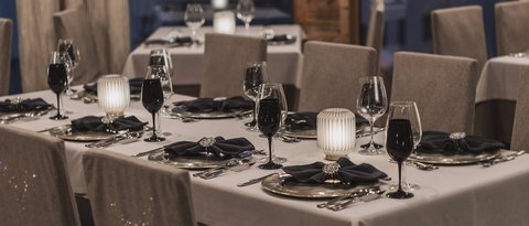 Bilder aus der Sportalm Elegantes Restaurant mit eingedeckten Tischen bei Abenddämmerung