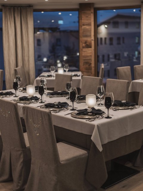 Bilder aus der Sportalm Elegantes Restaurant mit eingedeckten Tischen bei Abenddämmerung