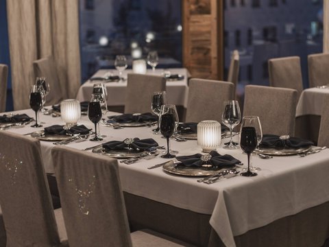 Bilder aus der Sportalm Elegantes Restaurant mit eingedeckten Tischen bei Abenddämmerung