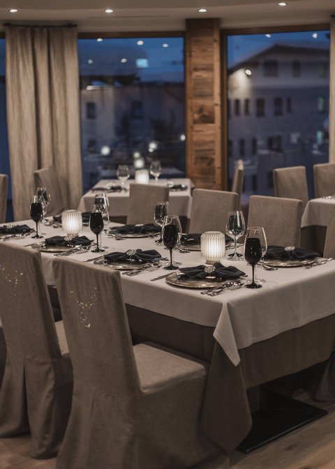 Bilder aus der Sportalm Elegantes Restaurant mit eingedeckten Tischen bei Abenddämmerung