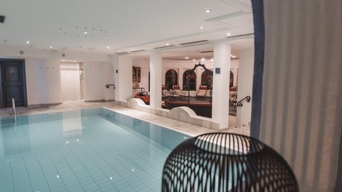 Bilder aus der Sportalm Innenbereich mit einem beleuchteten Swimmingpool und einer Kerze in einem dekorativen Käfig