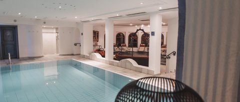 Bilder aus der Sportalm Innenbereich mit einem beleuchteten Swimmingpool und einer Kerze in einem dekorativen Käfig