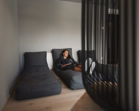 Bilder aus der Sportalm Frau entspannt auf grauem Liegesessel in modernem Raum