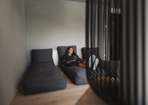 Bilder aus der Sportalm Frau entspannt auf grauem Liegesessel in modernem Raum