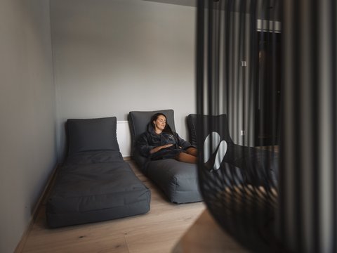 Bilder aus der Sportalm Frau entspannt auf grauem Liegesessel in modernem Raum