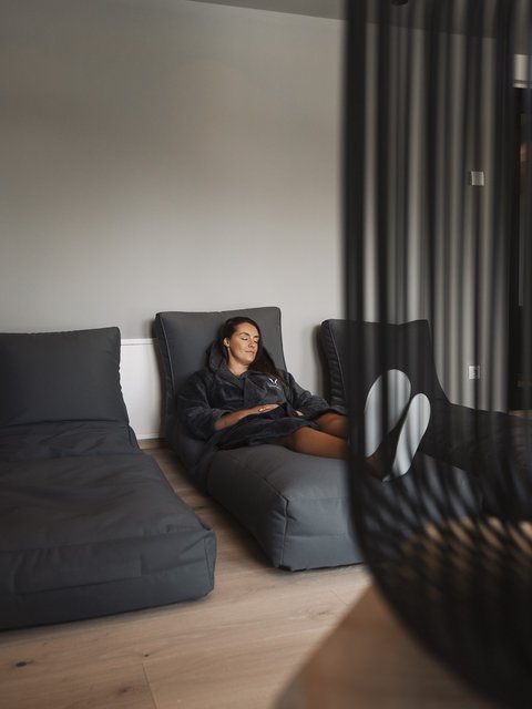 Bilder aus der Sportalm Frau entspannt auf grauem Liegesessel in modernem Raum