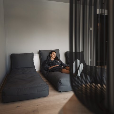 Bilder aus der Sportalm Frau entspannt auf grauem Liegesessel in modernem Raum