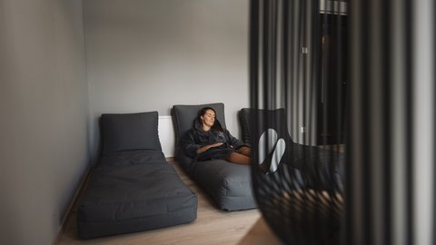 Bilder aus der Sportalm Frau entspannt auf grauem Liegesessel in modernem Raum