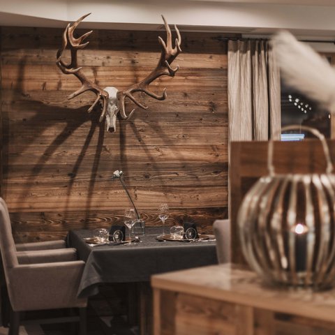 Bilder aus der Sportalm Gemütlicher Essbereich mit Hirschgeweih an der Holzwand und gedecktem Tisch