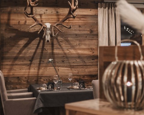 Bilder aus der Sportalm Gemütlicher Essbereich mit Hirschgeweih an der Holzwand und gedecktem Tisch