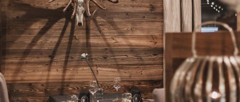 Bilder aus der Sportalm Gemütlicher Essbereich mit Hirschgeweih an der Holzwand und gedecktem Tisch