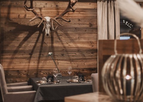 Bilder aus der Sportalm Gemütlicher Essbereich mit Hirschgeweih an der Holzwand und gedecktem Tisch