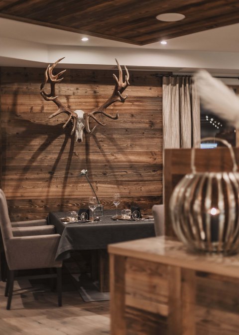 Bilder aus der Sportalm Gemütlicher Essbereich mit Hirschgeweih an der Holzwand und gedecktem Tisch