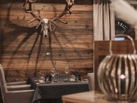 Bilder aus der Sportalm Gemütlicher Essbereich mit Hirschgeweih an der Holzwand und gedecktem Tisch