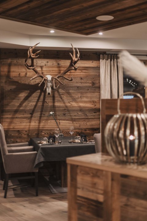 Bilder aus der Sportalm Gemütlicher Essbereich mit Hirschgeweih an der Holzwand und gedecktem Tisch