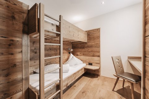 Bilder aus der Sportalm Kleines Zimmer mit Etagenbett und Holzverkleidung