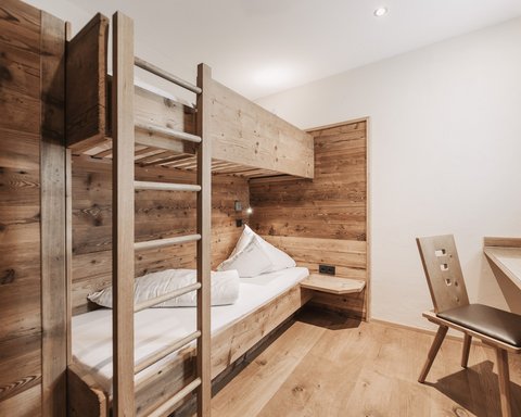 Bilder aus der Sportalm Kleines Zimmer mit Etagenbett und Holzverkleidung