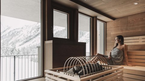 Bilder aus der Sportalm Frau entspannt in Sauna mit Blick auf schneebedeckte Berge