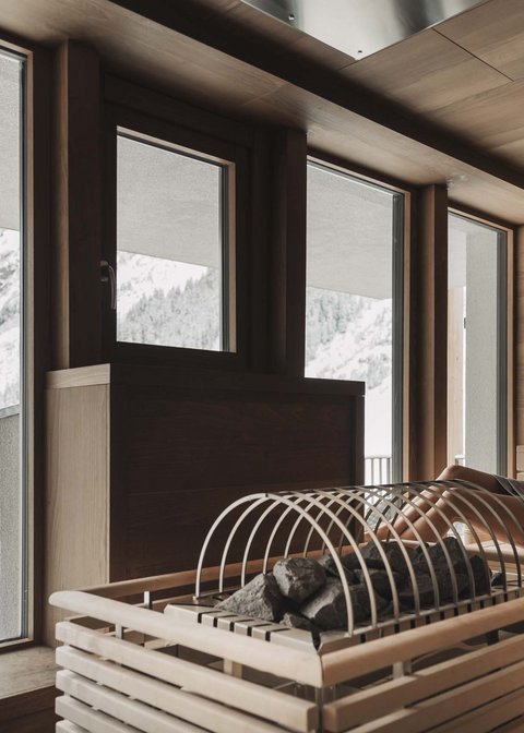 Bilder aus der Sportalm Frau entspannt in Sauna mit Blick auf schneebedeckte Berge
