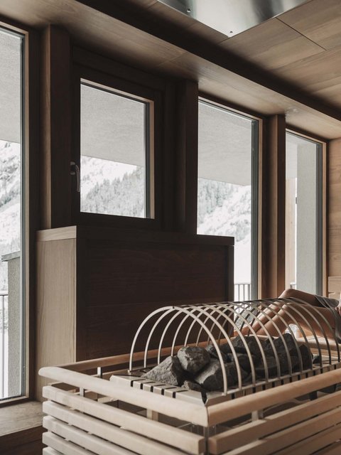 Bilder aus der Sportalm Frau entspannt in Sauna mit Blick auf schneebedeckte Berge