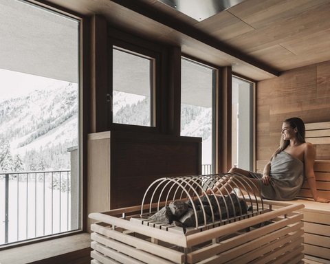 Bilder aus der Sportalm Frau entspannt in Sauna mit Blick auf schneebedeckte Berge