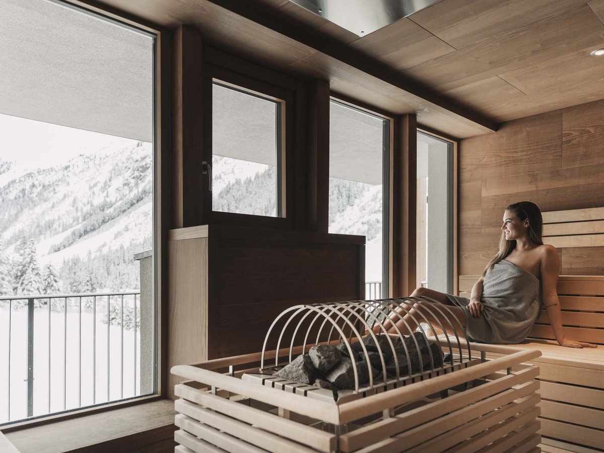 Wellness hotel in Pitztal: pure relaxation Woman relaxing in sauna overlooking snowy mountains