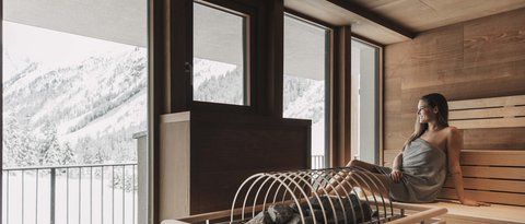 Bilder aus der Sportalm Frau entspannt in Sauna mit Blick auf schneebedeckte Berge