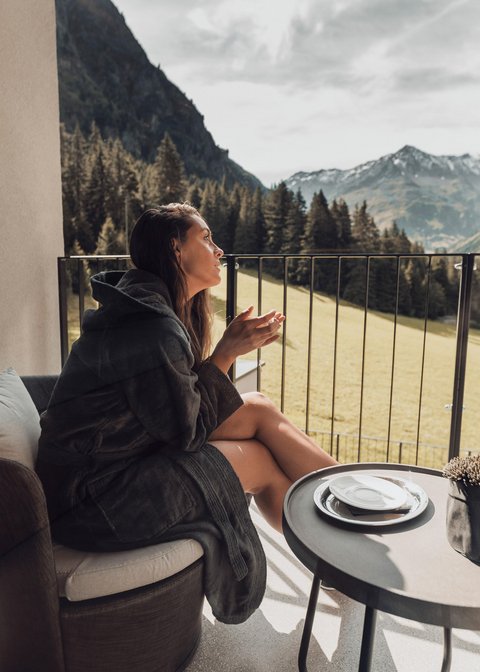 Pictures from Sportalm Woman in bathrobe sitting on balcony with mountain view at table