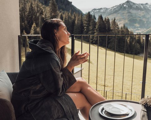 Pictures from Sportalm Woman in bathrobe sitting on balcony with mountain view at table