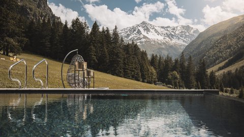 Bilder aus der Sportalm Pool mit Bergblick und hängendem Korbsessel an sonnigem Tag