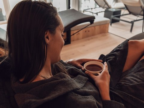 Pictures from Sportalm Woman relaxing in bathrobe drinking tea in a modern spa with a view