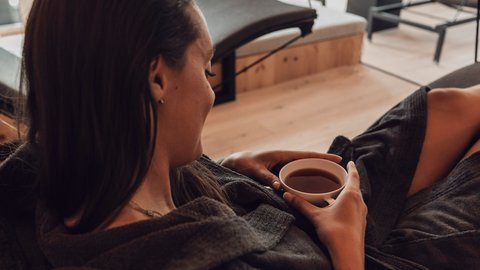 Pictures from Sportalm Woman relaxing in bathrobe drinking tea in a modern spa with a view